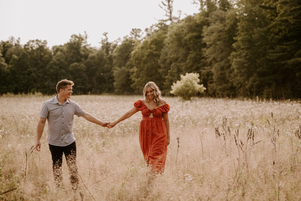 Brittany and her fiance hold hands in a field.