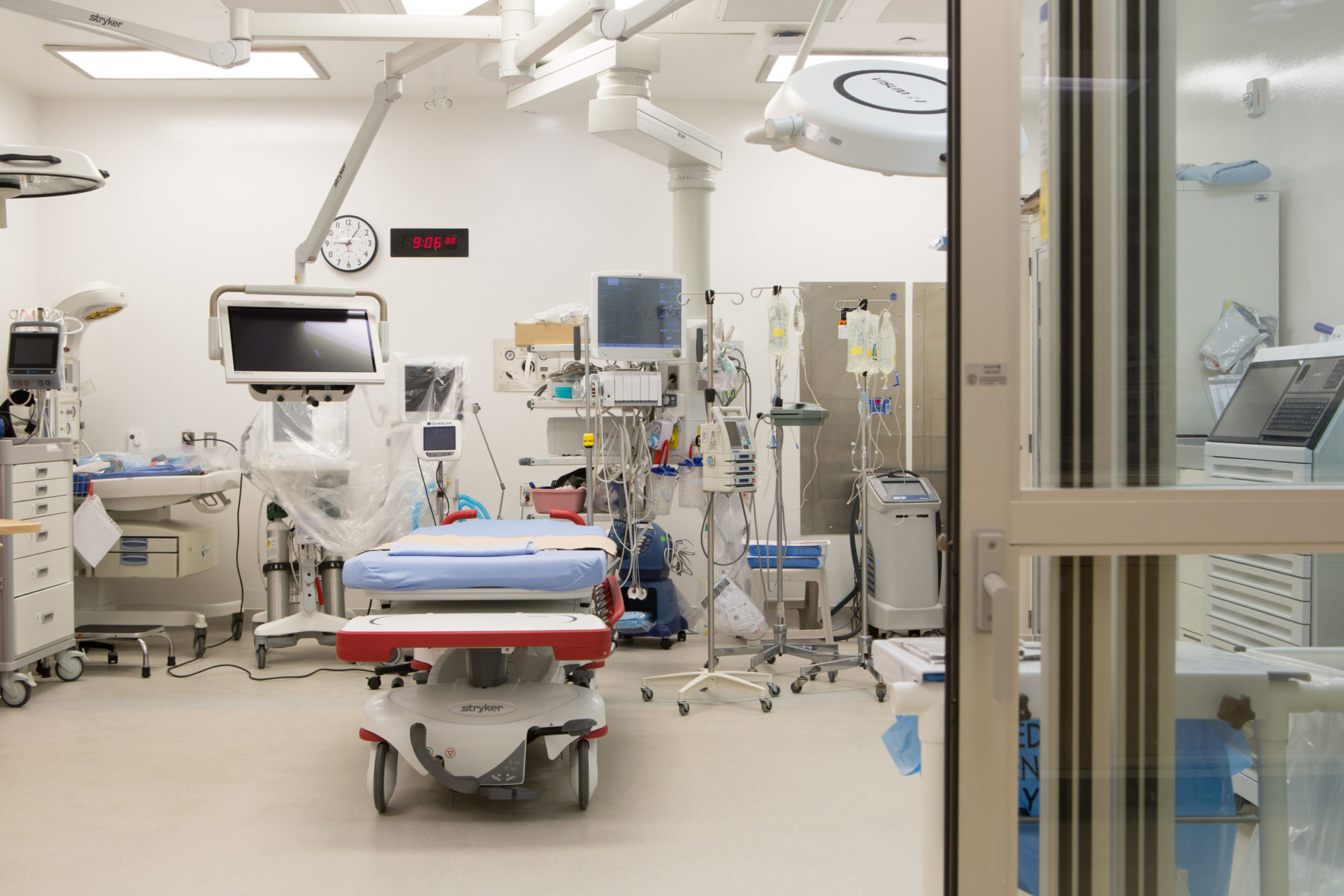 A picture of a negative pressure room in Humber River Hospital's Emergency Department. The room has a stretcher and lots of equipment, and the glass doors are sliding shut.