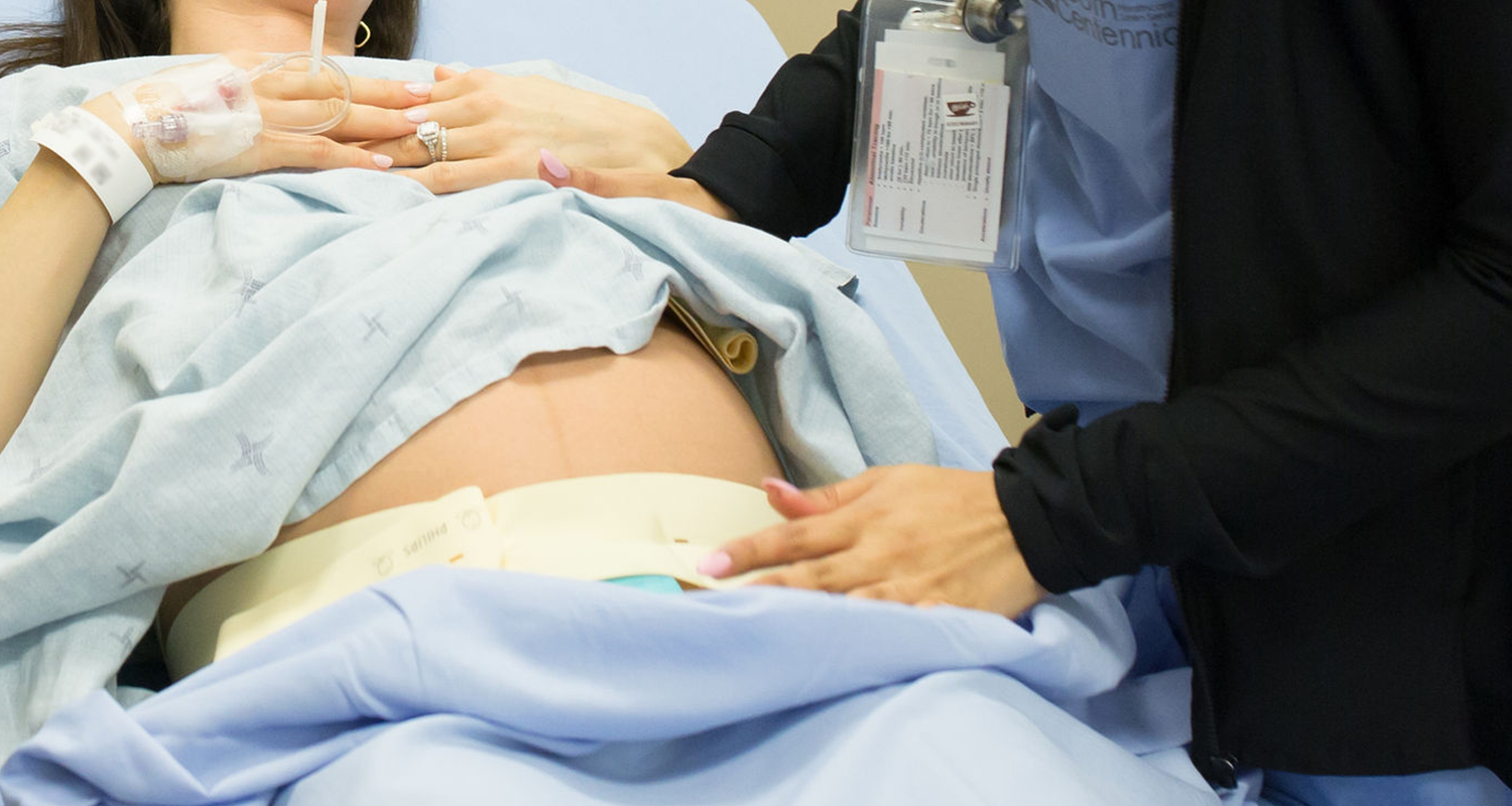 A nurse places her hands on her patient's belly