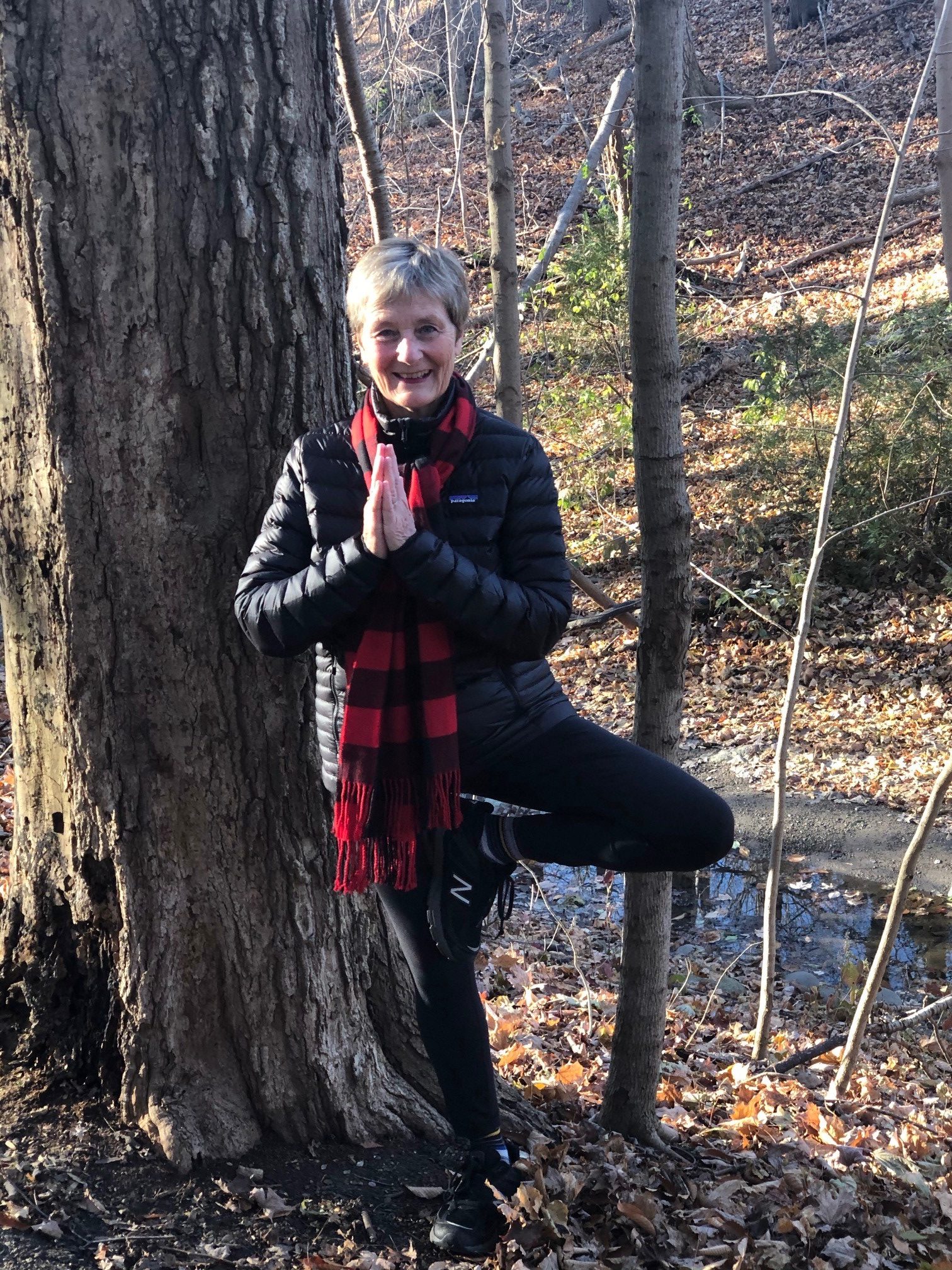 Wendy doing a tree pose in front of a tree