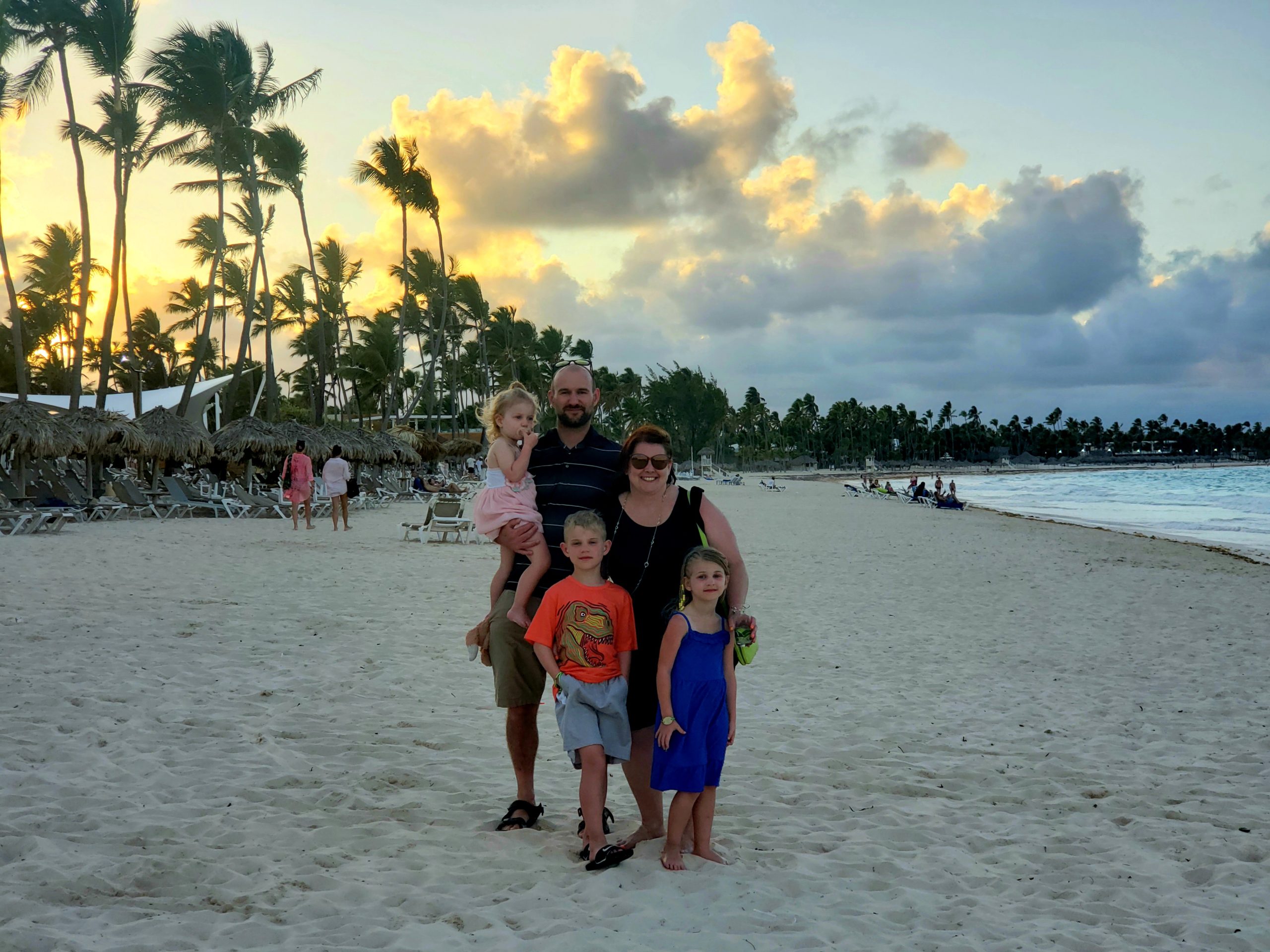 Danielle, her husband, and three kids smiling at the camera on a beach