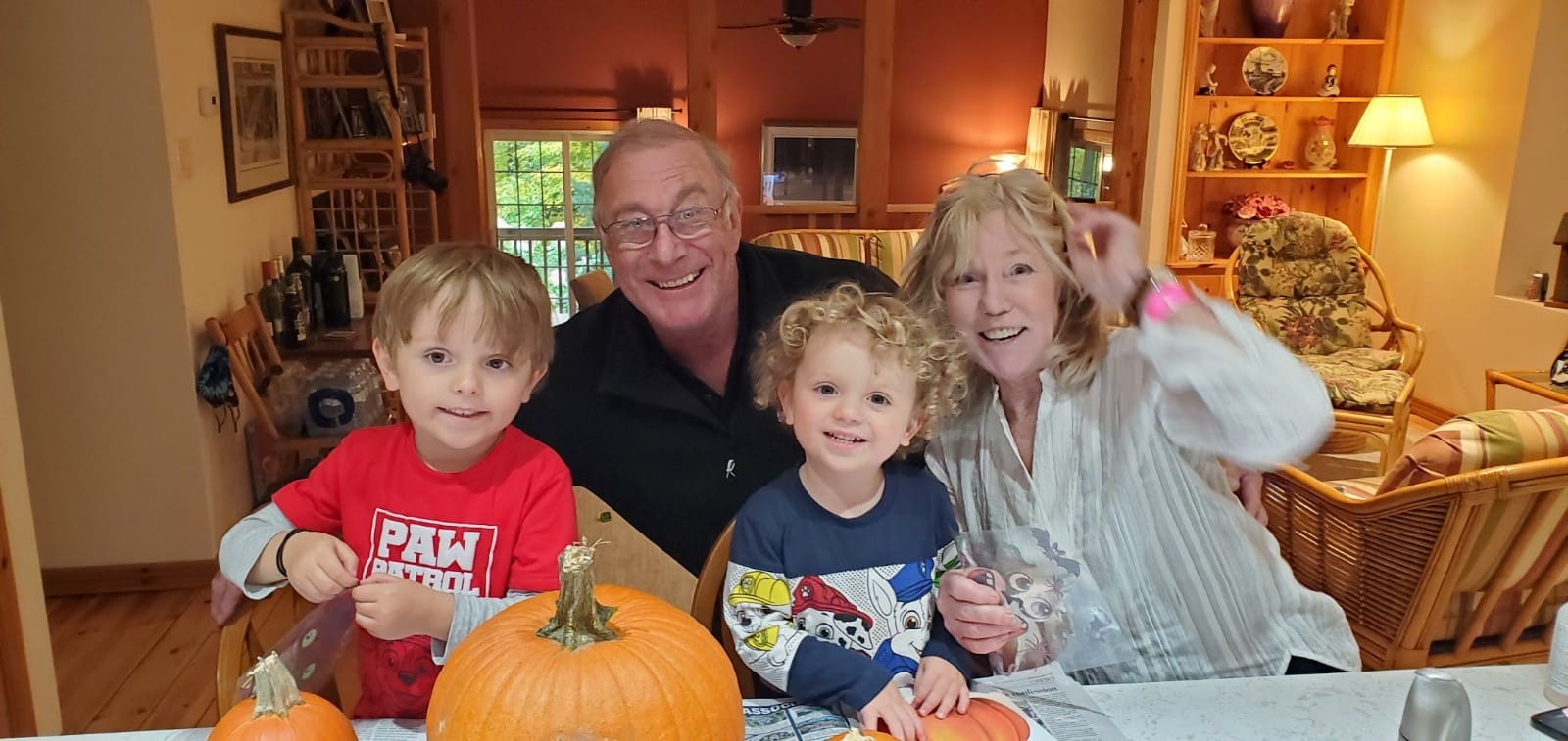 Wendy and her husband carve pumpkins with her two adorable grandkids