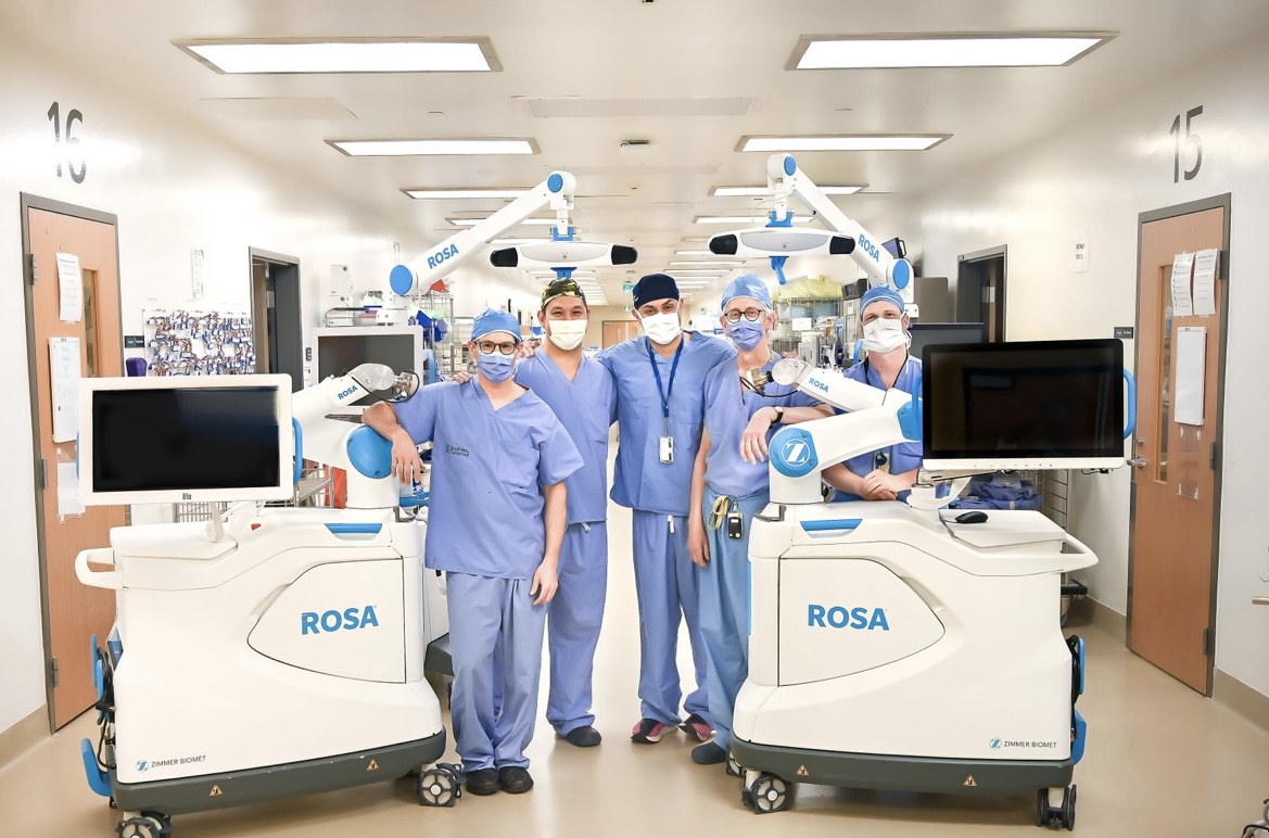 Surgeons pose with the two ROSA robots
